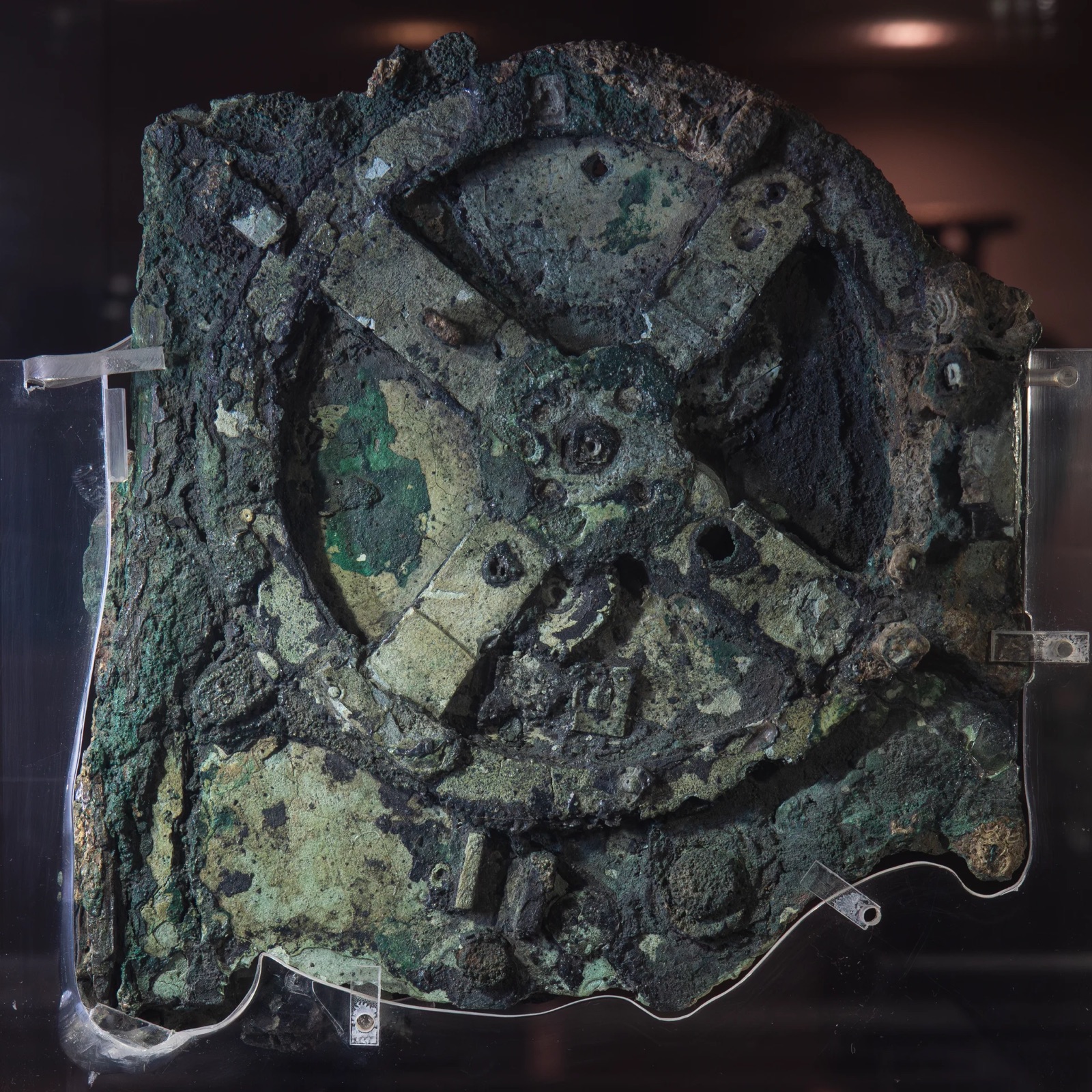 A corroded bronze fragment with visible gear wheels