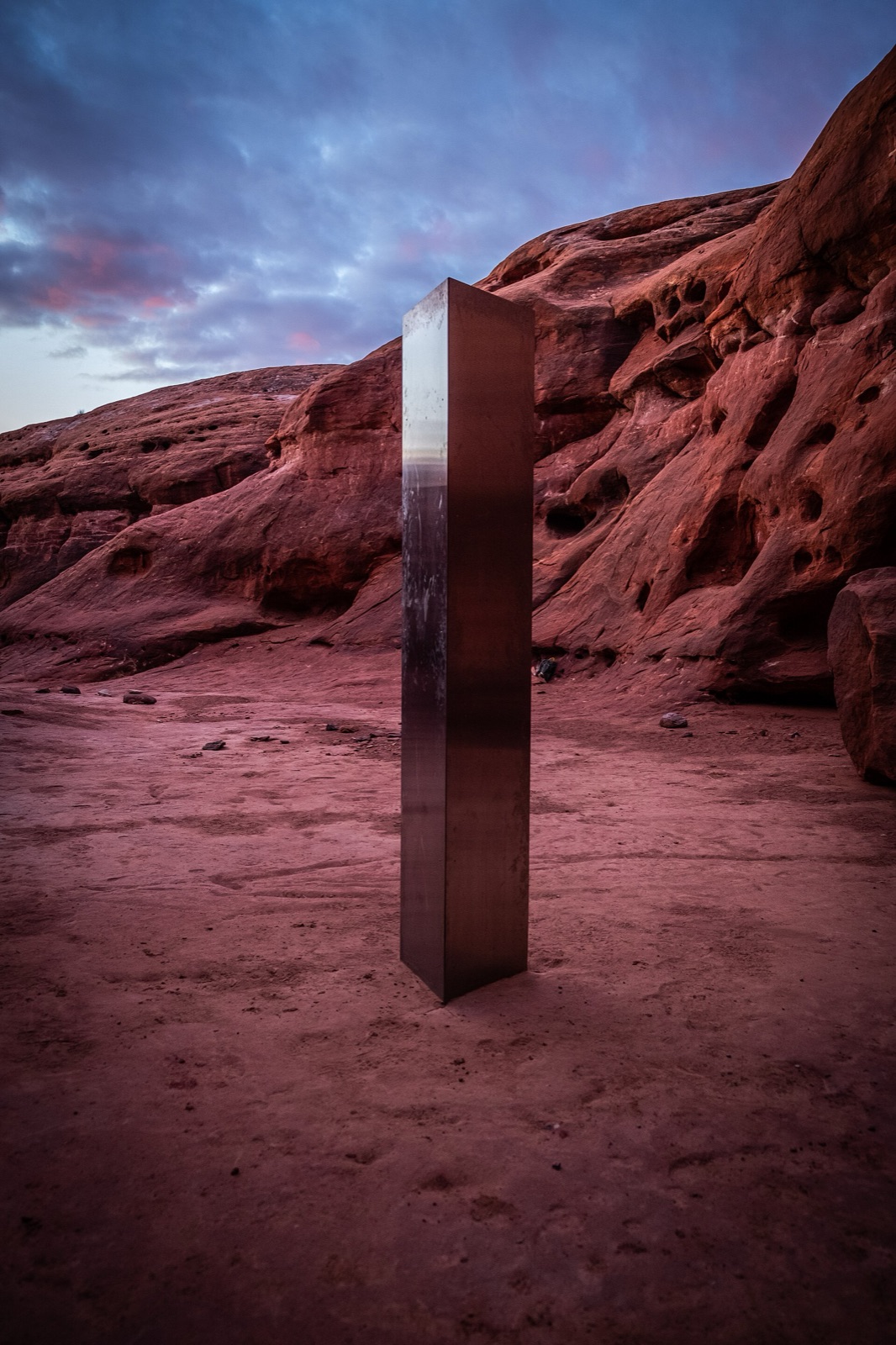 A tall metal monolith standing in a red rock canyon